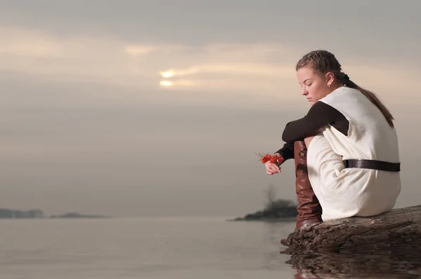 Одинокая женщина сидит на берегу озера — стоковое фото