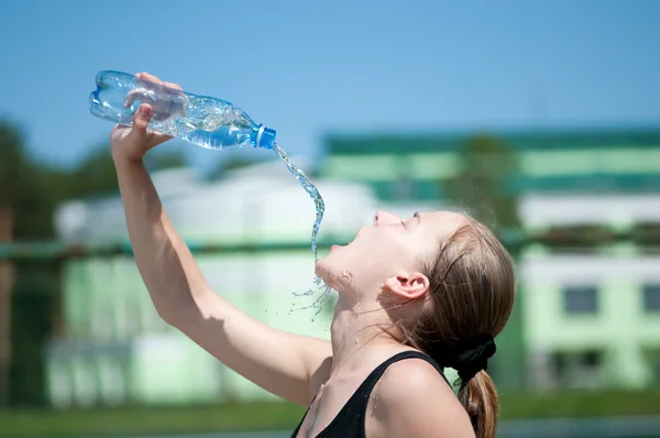 Mujer joven bebiendo agua después del ejercicio — Foto de Stock