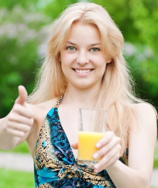 Mulher sorridente bebendo suco de laranja — Fotografia de Stock