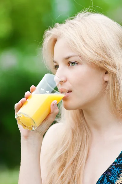 Lächelnde Frau trinkt Orangensaft — Stockfoto