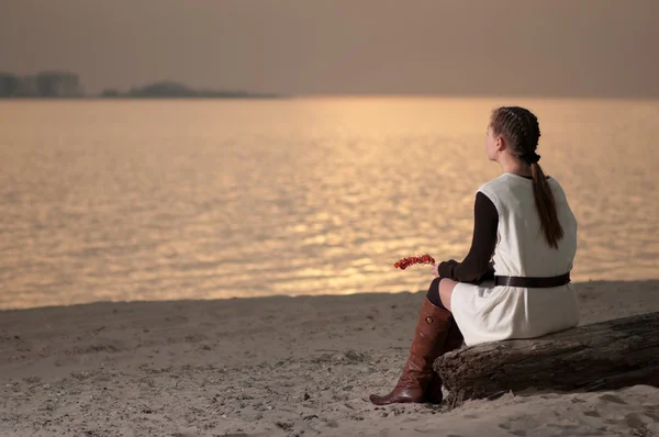 Samotna kobieta siedzi na wybrzeżu jeziora — Zdjęcie stockowe