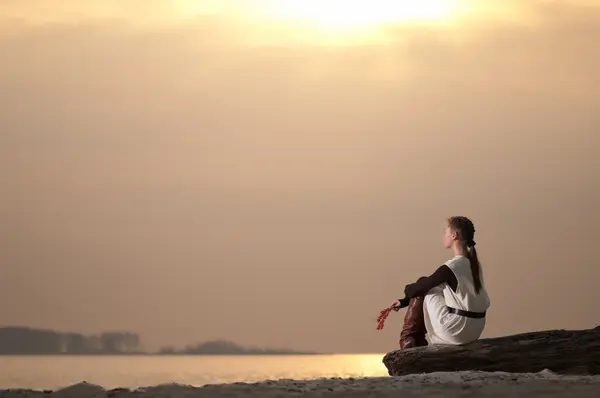 Lonely woman sitting on lake coast — Stock Photo, Image
