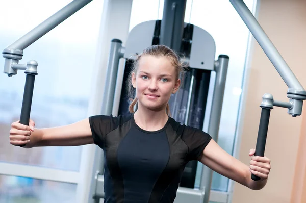 Mujer joven en el gimnasio haciendo ejercicio —  Fotos de Stock