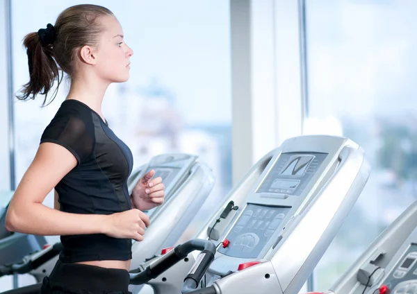 Une jeune femme au gymnase. Courir sur une machine — Photo