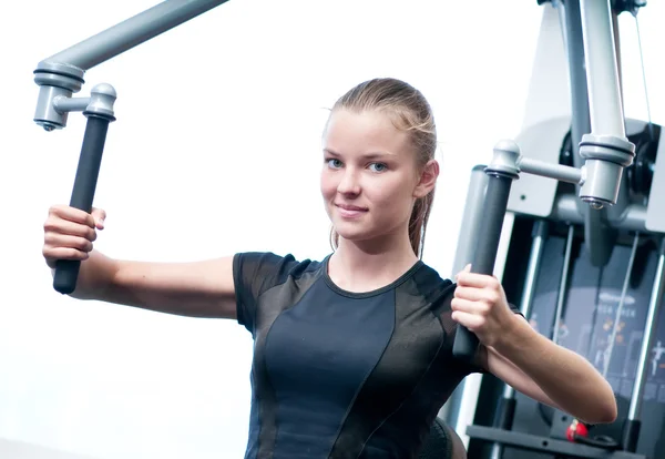 Mujer joven en el gimnasio haciendo ejercicio — Foto de Stock