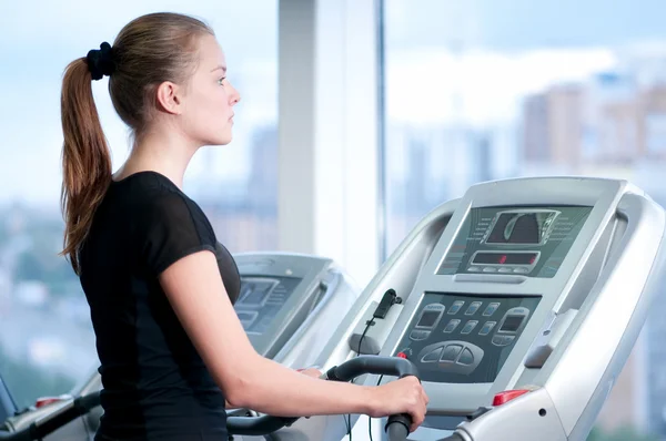 Spor salonunda genç bir kadın. bir makine üzerinde çalıştırmak — Stok fotoğraf