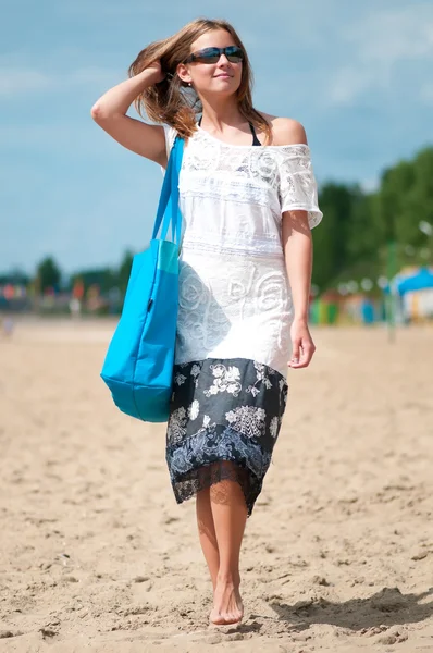 Mujer caminando en la playa de arena con bolsa — Foto de Stock