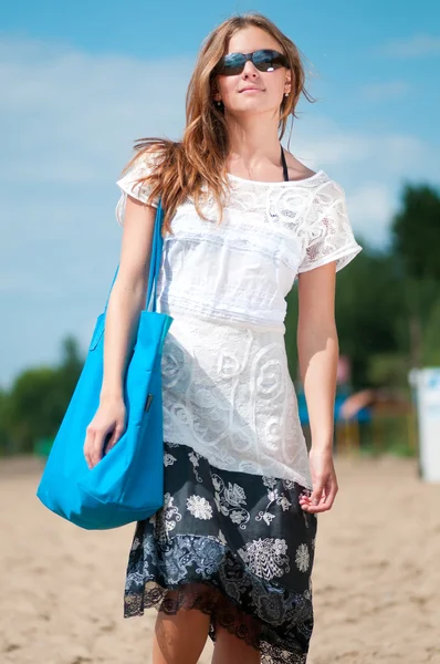 Mujer caminando en la playa de arena con bolsa — Foto de Stock