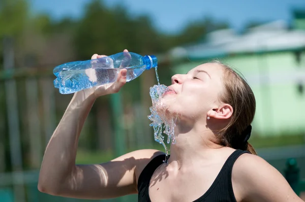 Mujer joven bebiendo agua después del ejercicio — Foto de Stock