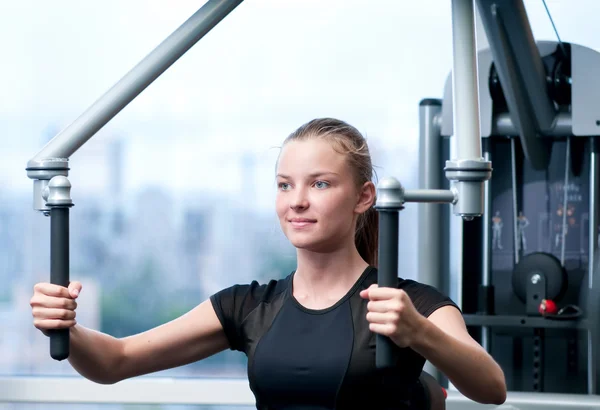 Mujer joven en el gimnasio haciendo ejercicio — Foto de Stock