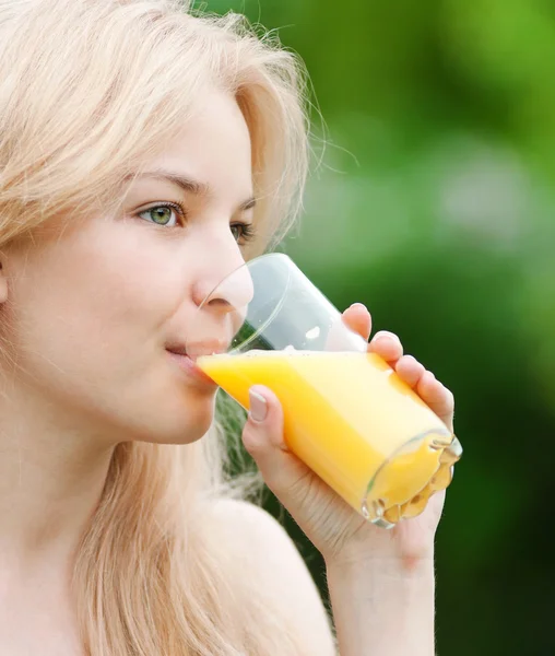 Lächelnde Frau trinkt Orangensaft — Stockfoto