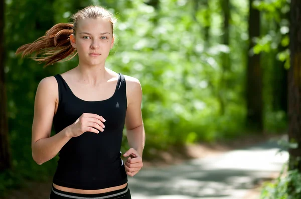 Жінка біжить в зеленому парку — стокове фото