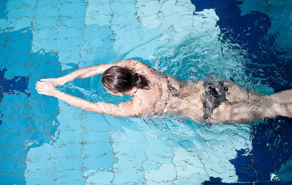 Athletic swimmer is diving in a swimming pool — Stock Photo, Image