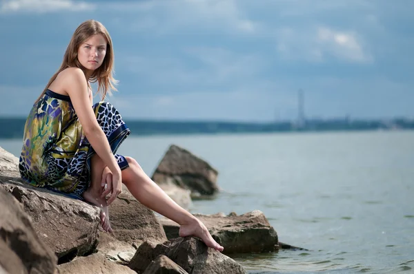 Smutna kobieta w sukni siedzi na skale — Zdjęcie stockowe