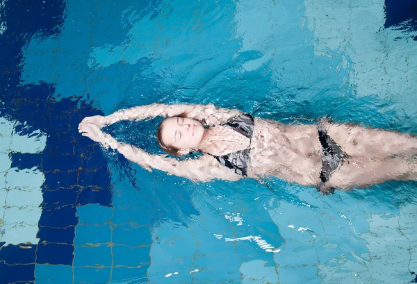 Swimmer in swim meet doing backstroke