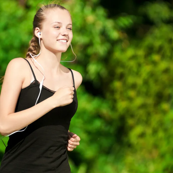 Jeune femme courant dans un parc vert Image En Vente