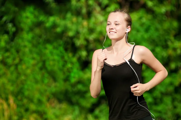 Young woman running in green park Stock Image