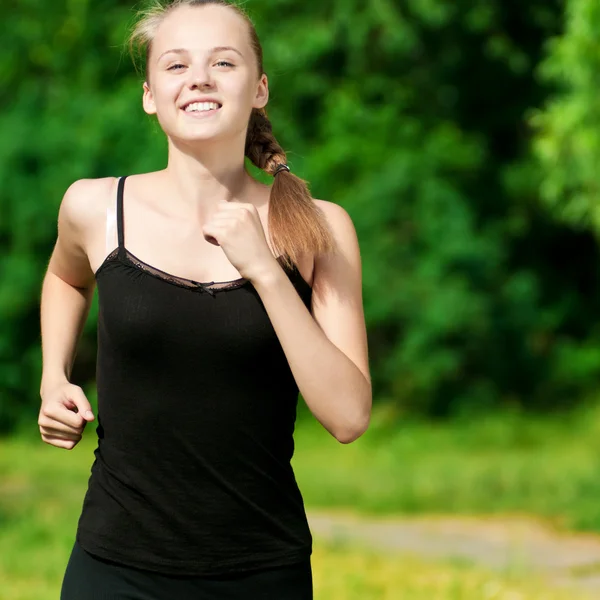 緑豊かな公園で走っている若い女性 ストック画像