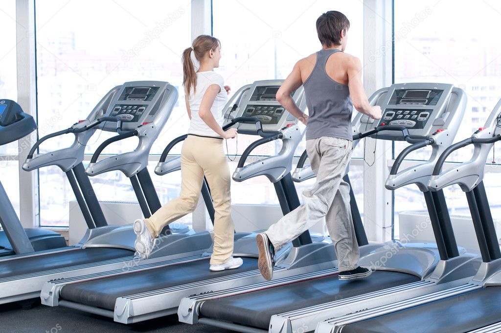Young woman and man at the gym exercising. Running