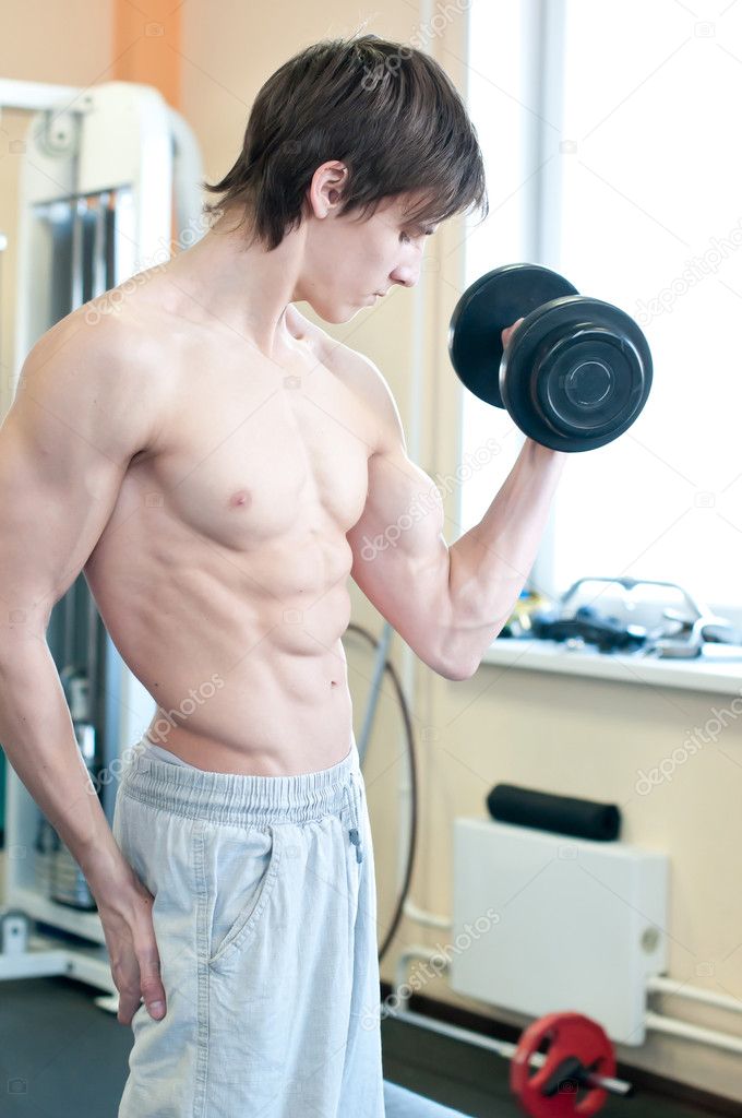Powerful muscular man lifting weights in gym