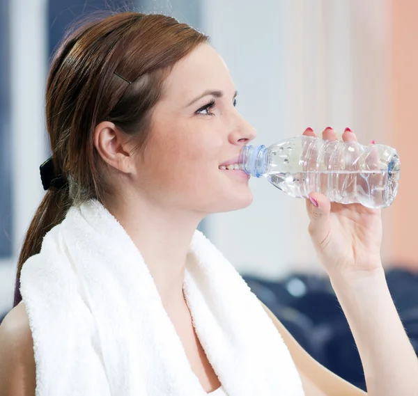 Vacker sport kvinna dricka vatten på gym — Stockfoto