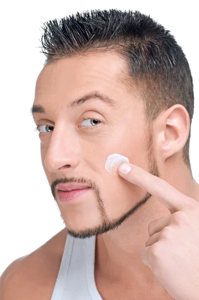 Bonito homem aplicando creme masculino no rosto — Fotografia de Stock