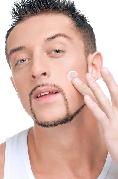 Bonito homem aplicando creme masculino no rosto — Fotografia de Stock