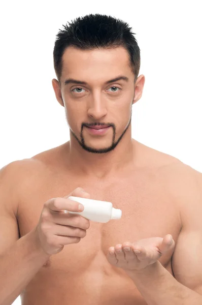 Junger Mann cremt sich ein. Kosmetik — Stockfoto