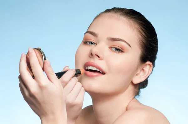 Schöne junge erwachsene Frau, die kosmetischen Lippenstift aufträgt — Stockfoto