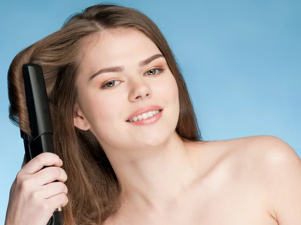 Close up portrait of young woman with hair iron — Stock Photo, Image
