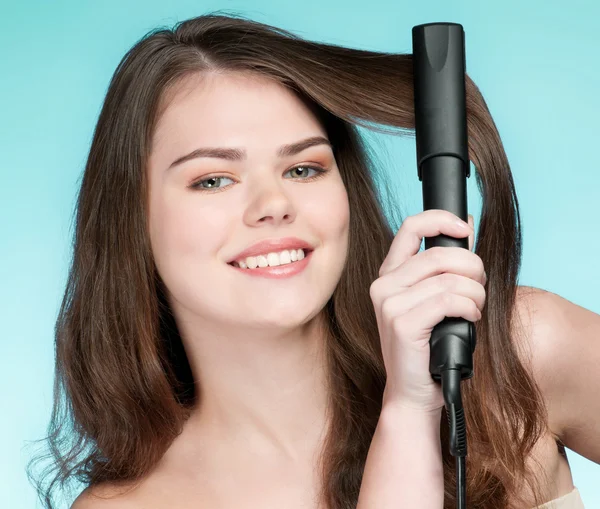 Закрыть портрет молодой женщины с утюгом для волос — стоковое фото