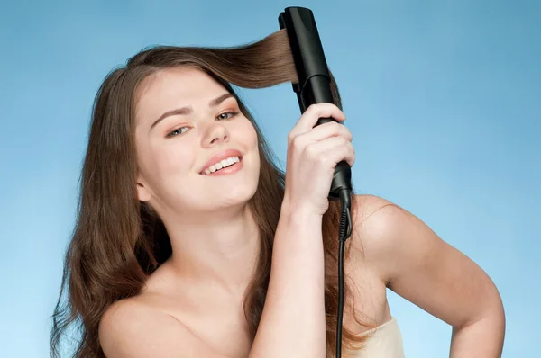 Закрыть портрет молодой женщины с утюгом для волос — стоковое фото
