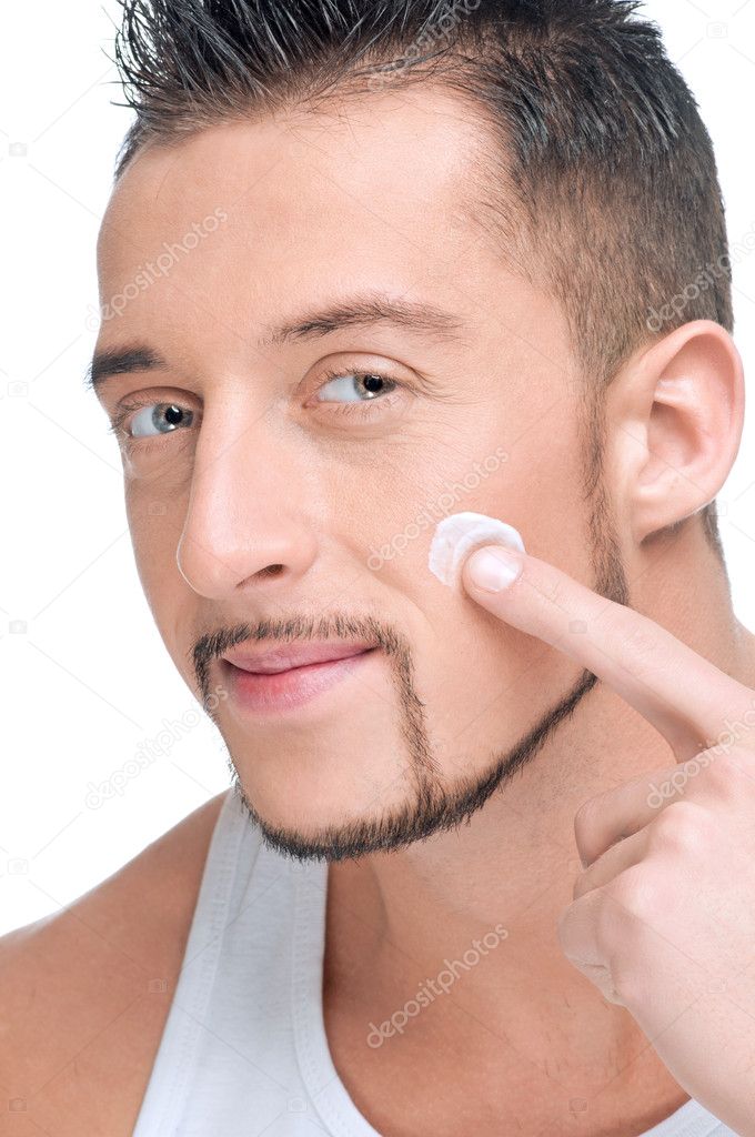 Handsome man applying male creme on face