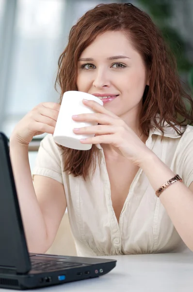 Mujer de negocios con un ordenador portátil y taza —  Fotos de Stock