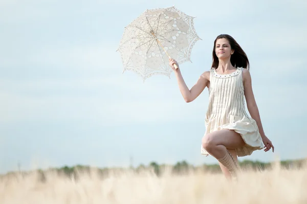 Сумна жінка з парасолькою біжить у полі — стокове фото