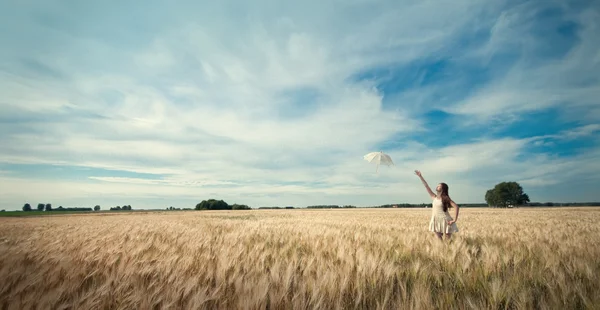 Frau mit Regenschirm läuft auf Feld. — Stockfoto