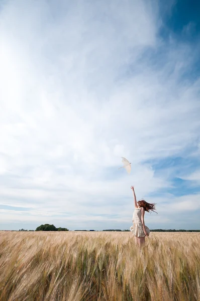 Woman with umbrella walking in field. — Stock Photo, Image