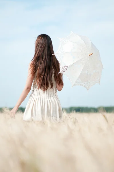 Vrouw met paraplu wandelen in veld. — Stockfoto