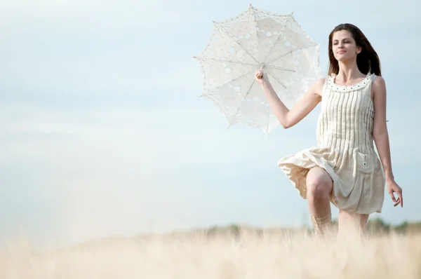 Sad woman with umbrella runing in field — Stock Photo, Image