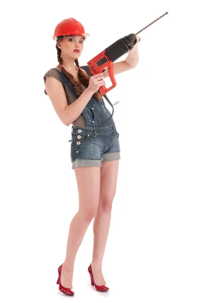 Młoda kobieta zabawy w dżinsy kombinezon posiadający wiertarki udarowe — Zdjęcie stockowe