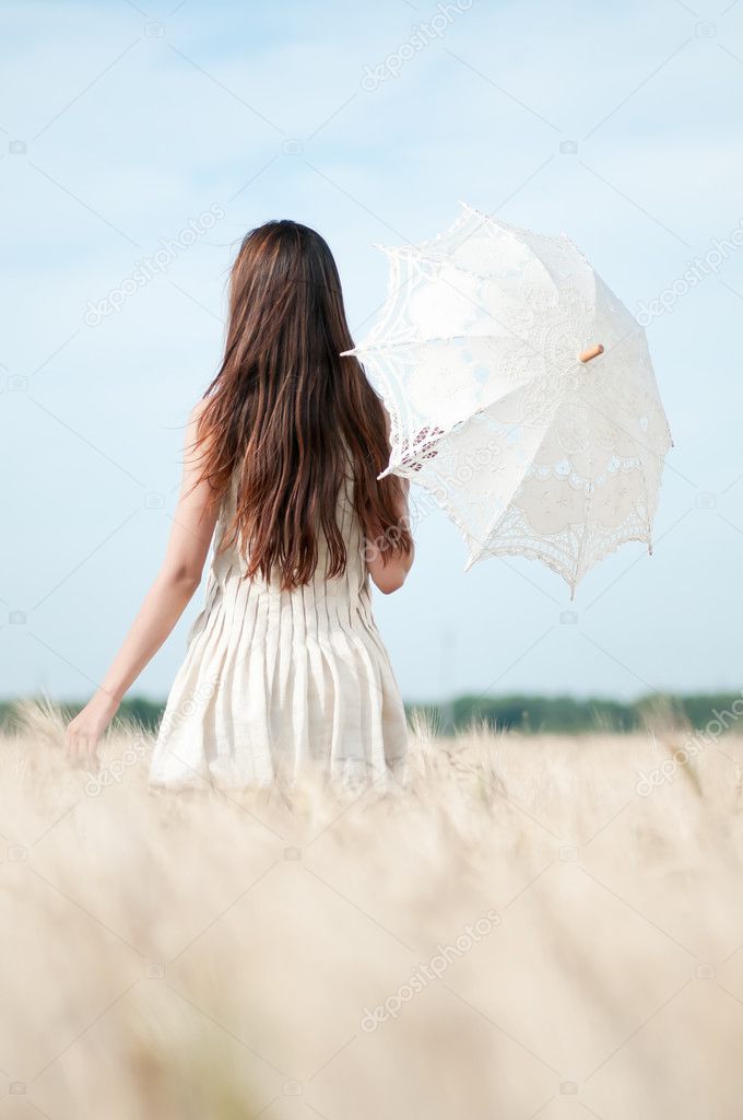 Woman with umbrella walking in field.