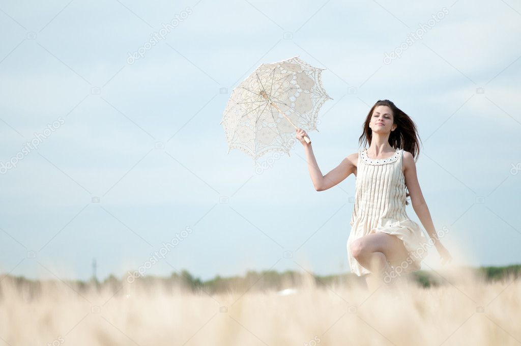 Sad woman with umbrella runing in field