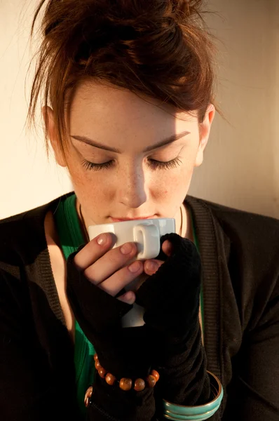 Красивая молодая женщина с чашкой кофе над окном — стоковое фото
