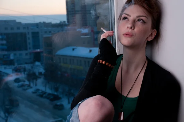 Hermosa joven fumando en la ventana de la noche . —  Fotos de Stock