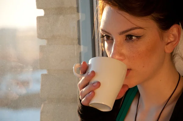 Mulher bonita com xícara de café sobre janela — Fotografia de Stock