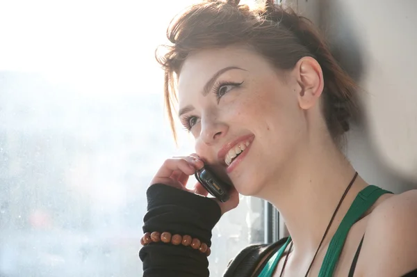 Gyönyörű fiatal nő, sejt telefon-ra ablak. — Stock Fotó