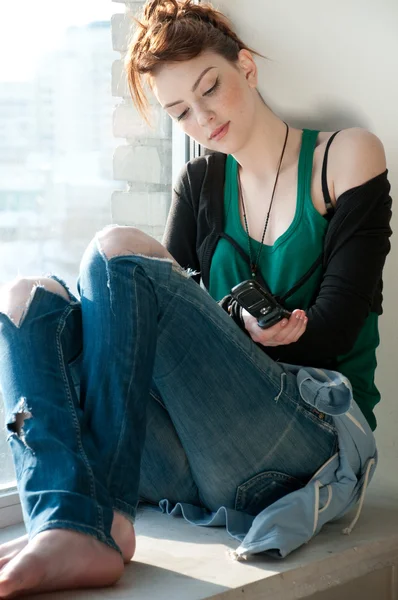 Pencere cep telefonu ile güzel bir genç kadın. — Stockfoto