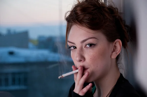 Mulher bonita fumando na janela da noite . — Fotografia de Stock