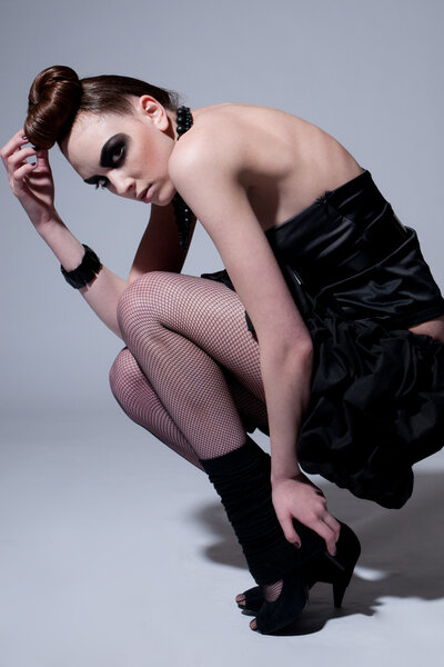Studio shot of a young, beautiful, fashion model with black make-up, dress and beads