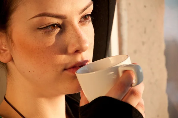 Hermosa joven con taza de café sobre la ventana —  Fotos de Stock